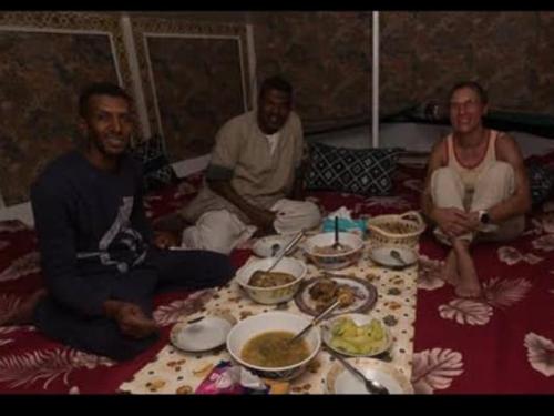 un grupo de tres hombres sentados alrededor de una mesa con comida en My Dream Nile Felucca en Asuán