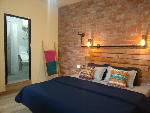 a bedroom with a brick wall and a bed with pillows at White Rabbit Guest House in Dharamshala