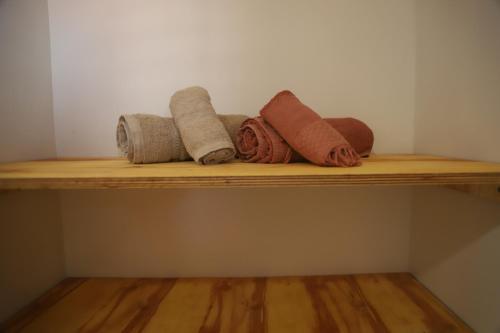 a wooden shelf with four rolled towels on it at Zero Meia Um Pousada in São Miguel do Gostoso