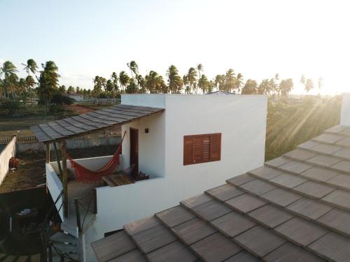 a white house with a window and a roof at Zero Meia Um Pousada in São Miguel do Gostoso