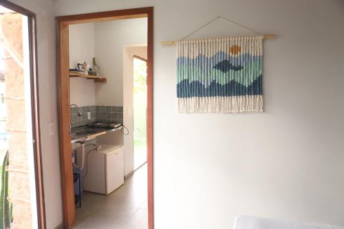 a door leading into a kitchen with a painting on the wall at Zero Meia Um Pousada in São Miguel do Gostoso