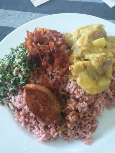 a plate of food with rice and meat and vegetables at Gimhana farmstay in Ihalawewa