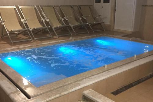 a pool of blue water in a bathroom with chairs at Casthotels Bristol Terme in Ischia