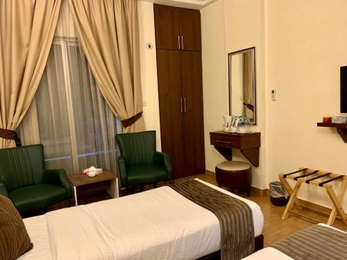 a hotel room with two beds and a desk and chairs at Ream Hotel Amman in Amman
