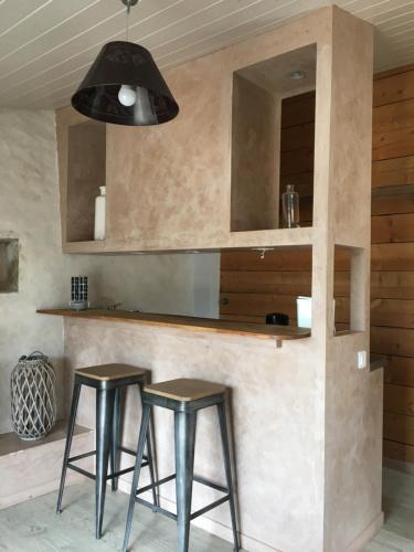 une cuisine avec deux tabourets devant un comptoir dans l'établissement Gîte «Les frênes », à Marigny