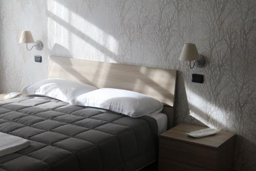 a bedroom with a bed with a head board and lamps at Cà del Crutin in Monteu Roero