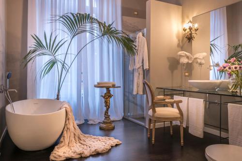 ein Badezimmer mit einer Badewanne, 2 Waschbecken und einer Pflanze in der Unterkunft Arnaboldi Palace in Pavia