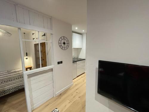 a living room with a tv and a clock on a wall at Charmant 2 pièces cosy au cœur de Saint-Gervais in Saint-Gervais-les-Bains