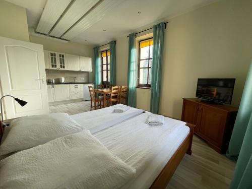 a bedroom with a large white bed and a kitchen at Apartamenty Przy Parku in Rabka-Zdrój