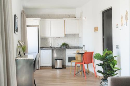 a kitchen with white cabinets and a table and chairs at Hotel Ventus in El Médano