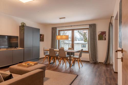 sala de estar con mesa, sillas y sofá en Finest Villa Zell am See by All in One Apartments, en Zell am See