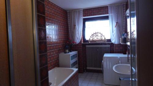 baño con bañera, lavabo y ventana en Großzügige Wohnung mit Terrasse und Gartenzugang., en Bindlach