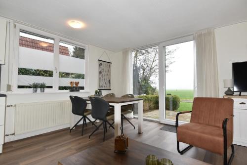 a kitchen and dining room with a table and chairs and windows at Vakantiehuis Tjeukemeer, de Friese Meren in Rohel