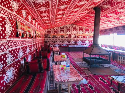 una stanza rossa con tavoli e sedie e un camino di Red Mountain Camp a Wadi Rum