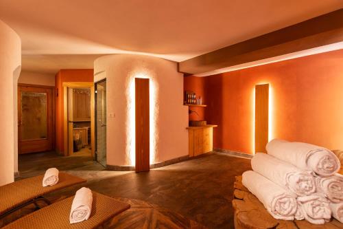a room with orange walls and white towels at Alpenhotel La Montanara in Rocca Pietore