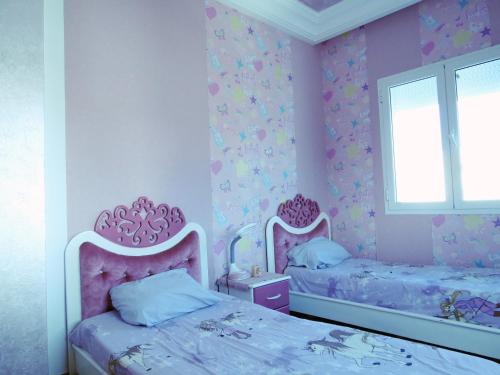 a pink bedroom with two beds and a window at Beautiful appartment with a glorious sea view in Monastir