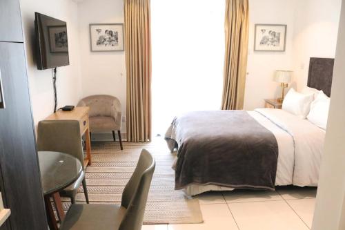 um quarto de hotel com uma cama, uma mesa e uma cadeira em APARTMENTS GH - Accra - Cantonments - Embassy Gardens em Acra