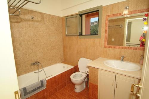 a bathroom with a tub and a toilet and a sink at GARDEN VILLAS in Ayia Evfimia