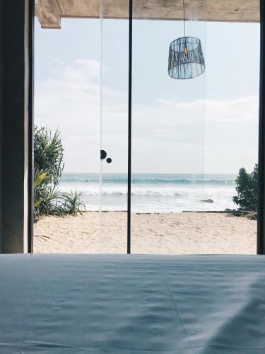 a room with a view of the beach through windows at Morena Boutique Hotel Weligama in Midigama