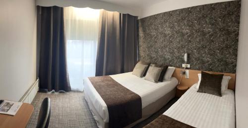 a hotel room with two beds and a window at The Originals City, Hôtel Villancourt, Grenoble Sud in Le Pont-de-Claix