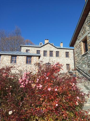 a large stone building with a flowering bush in front of it at Guesthouse Kontogianni - Materka in Nymfaio