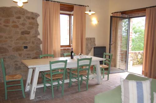 a dining room with a table and green chairs at Podere Campovecchio in Rapale