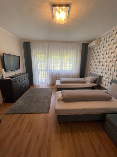 a room with two beds and a tv and a couch at Thermal Next I Weninger Apartman Kiskunhalas in Kiskunhalas