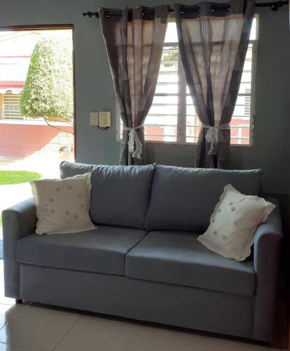 a blue couch with pillows in a living room at CASITA HOGAREÑA JARABACOA (independent entrance) in Jarabacoa