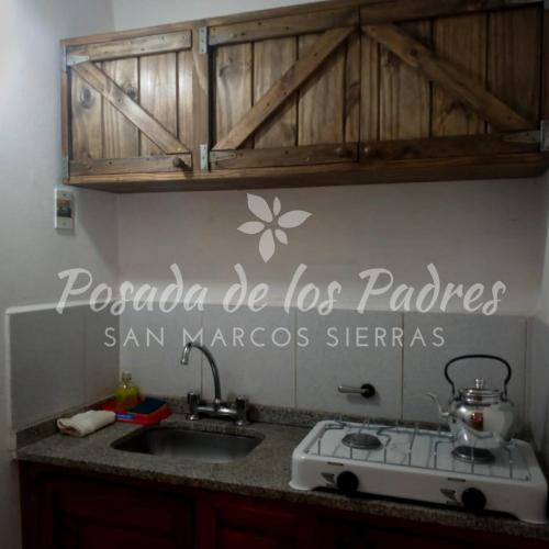 a kitchen with a stove and a sign on the wall at Posada de los Padres - LOS OLIVOS in San Marcos Sierras