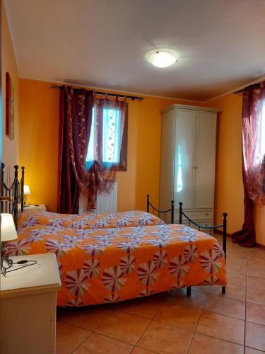 a bedroom with two beds with orange walls and windows at Agriturismo Il Melograno in Tessera