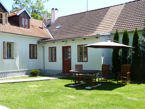 a table and chairs and an umbrella in a yard at Penzion U Houšků in Stráž nad Nežárkou