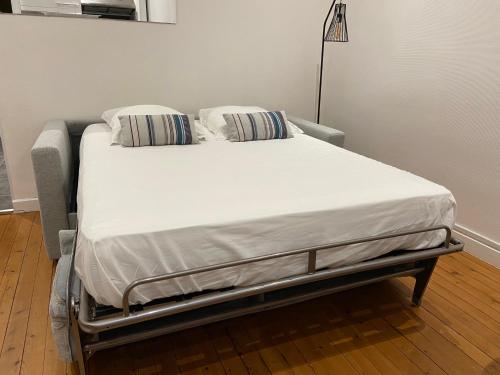 ein Krankenhausbett mit weißer Bettwäsche und Kissen darauf in der Unterkunft Studio (Coup de Coeur) Wimereux in Wimereux