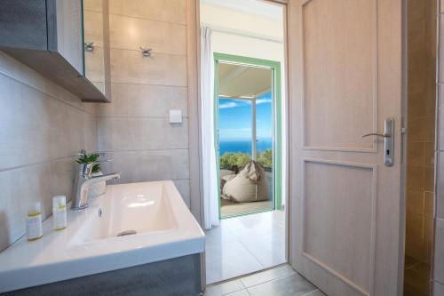 a bathroom with a sink and a door with a view at Villa Alma in Kalamitsi