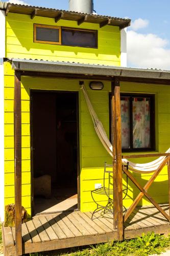 a yellow house with a chair on a porch at Cabañas Puerto Surf in Mar del Plata
