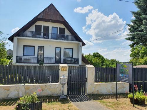 uma casa branca com uma cerca preta em Sipos Vendég és Apartmanház em Balatongyörök