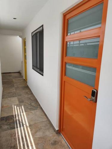 an orange door in a room with a hallway at Naranja Departamento 33 M2 nuevo in Jiutepec