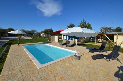 una piscina con due ombrelloni e due sedie di Bella di Campo a Rovigno (Rovinj)