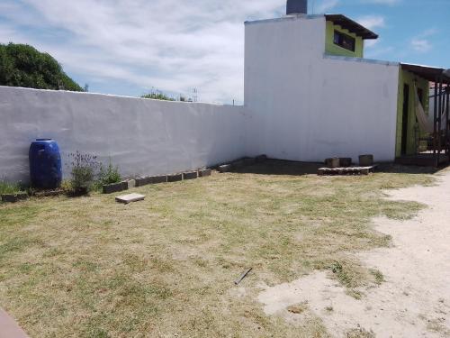 a white building with a yard next to a wall at Cabañas Puerto Surf in Mar del Plata