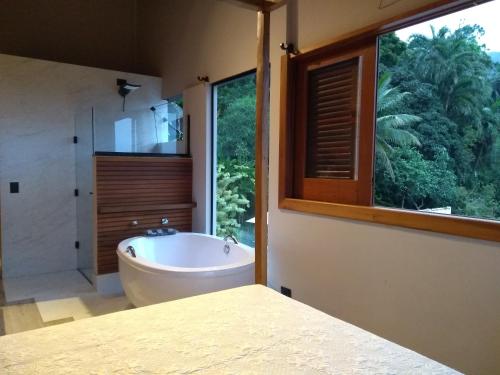 a bathroom with a tub and a large window at El Shadday Pousada Boutique in Ubatuba