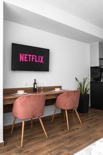 a table with two chairs and a netflix sign on a wall at Adelle Apartments, The Luxury Suites in Thessaloniki