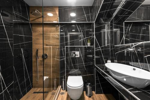 a black tiled bathroom with a toilet and a sink at Adelle Apartments, The Luxury Suites in Thessaloniki