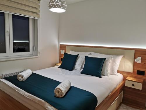 ein Schlafzimmer mit einem großen Bett mit blauen und weißen Kissen in der Unterkunft Apartman Maximus in Vrnjačka Banja