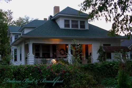 a woman sitting on the porch of a house at Delano Bed and Breakfast in Wichita
