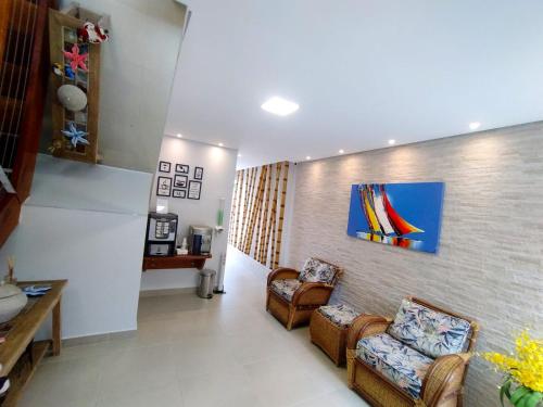 a living room with two chairs and a painting on the wall at Aldeia Da Lagoinha in Ubatuba