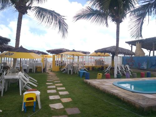 a resort with a pool and chairs and palm trees at Girassol Pousada in Extremóz