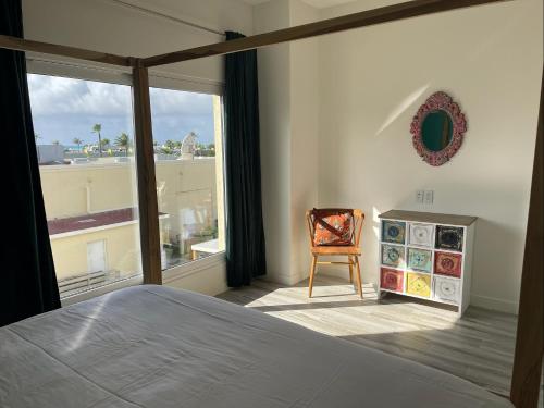 a bedroom with a bed and a chair and a window at Luxury Ocean view Condo @ Aruba’s Palm Beach in Palm-Eagle Beach