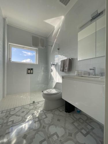 a white bathroom with a toilet and a sink at Luxury Ocean view Condo @ Aruba’s Palm Beach in Palm-Eagle Beach