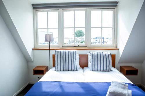 a bedroom with a bed with two pillows and a window at Hotel Café Restaurant Heineke in Loosdrecht