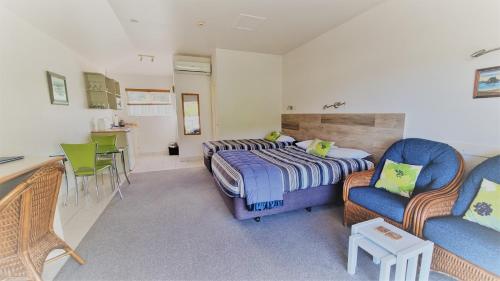 a bedroom with a bed and chairs and a kitchen at Admirals View Lodge in Paihia