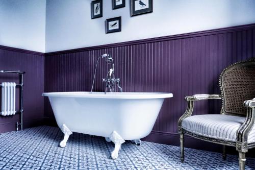 a white bath tub in a purple bathroom with a chair at Edmondstown House in Ballaghaderreen